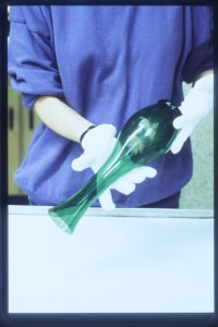 A conservator wearing gloves handling a glass vase